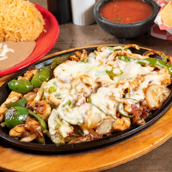 Sizzling chicken fajitas with melted cheese, green peppers, and onions, served with rice and beans.