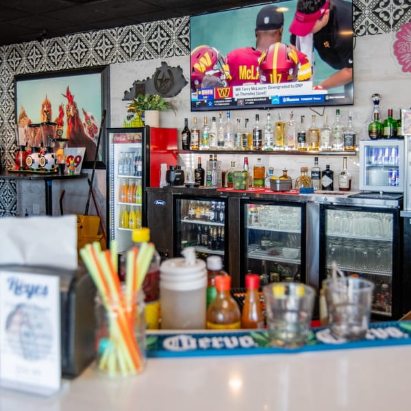 Reyes Mexican Grill bar area with liquor bottles, refrigerators, and a TV showing football.