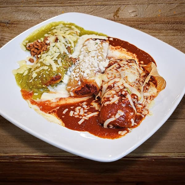 A white plate of Reyes Mexican Grill enchiladas, one with green sauce, one with white sauce, and one with red sauce.